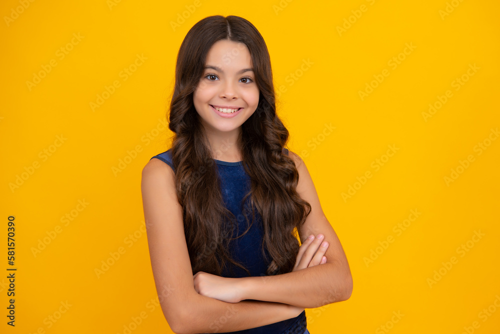 Obraz premium Happy girl face, positive and smiling emotions. Teenage girl kid with crossed arms, looking at camera, isolated on yellow studio background.
