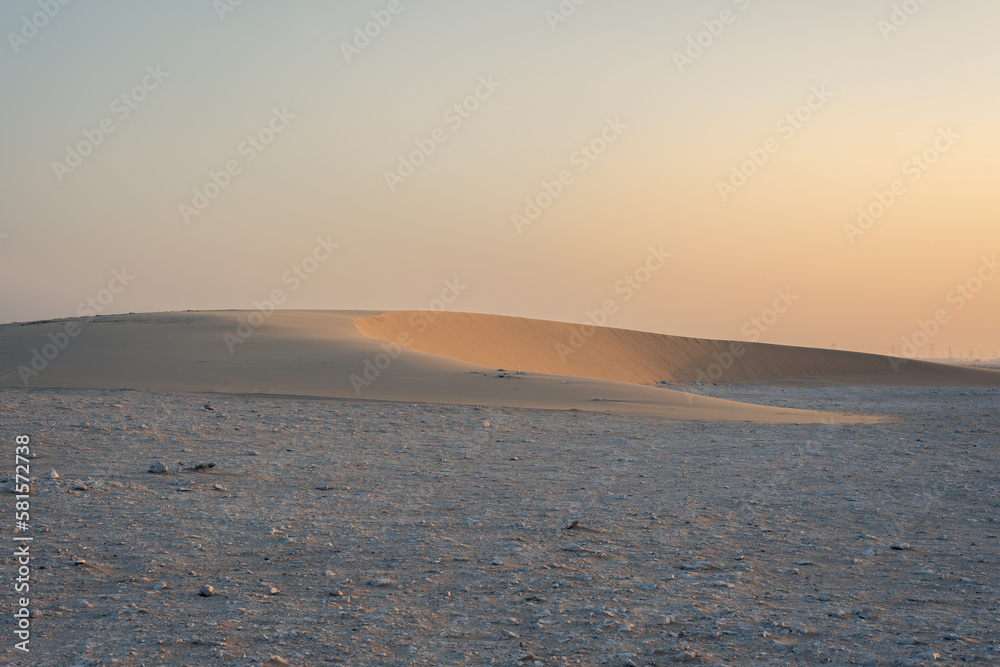 SIngle sand dune sitting on rocky ground, sunny side of the dune looks so soft, golden, golden hour, sand dune in the middle east, desert