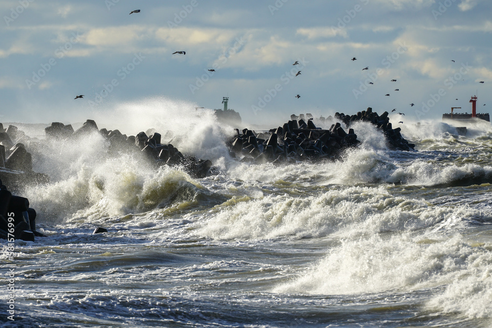 Coastal storm in the Baltic Sea, big waves crash against the harbor breakwater, breaking wave