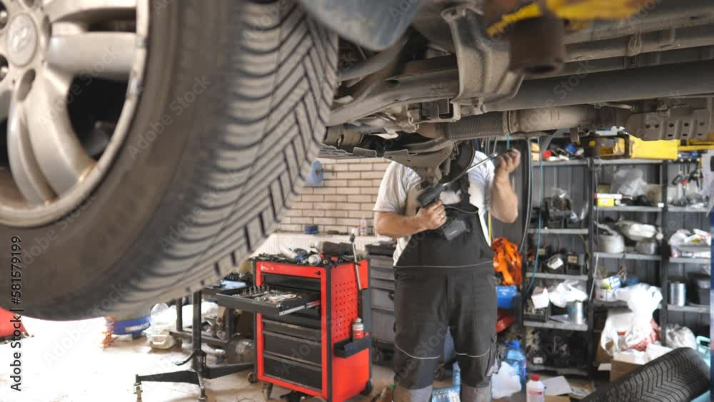custom made wallpaper toronto digitalProfessional auto mechanic working underneath a lifting vehicle at garage. Unrecognizable repairman repairing car with special tool at workshop. Concept of automobile maintenance. Slow motion