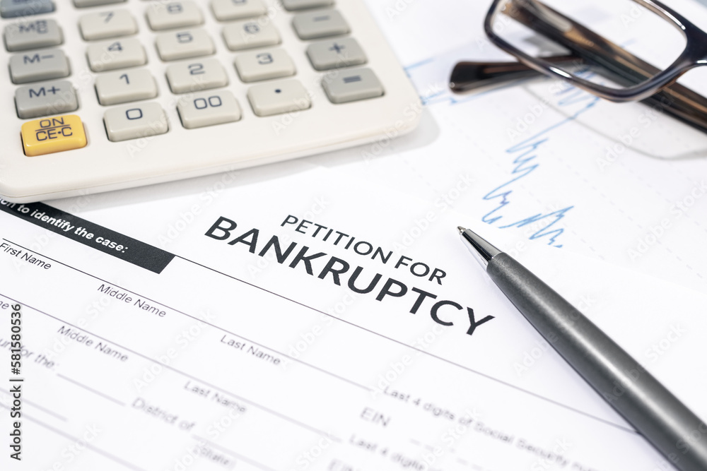 Bankruptcy form, calculator and pen on desk. Personal injury claim form Bankruptcy form, calculator and pen on desk. Personal injury claim form