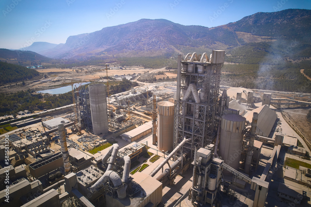 Huge cement producing plant. Aerial view of silos towers, pipes and other structures of industrial area