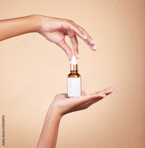 Hands, product and antiaging serum with a woman in studio on a beige background to promote skincare. Marketing, advertising and luxury with a female holding a bottle for the promotion of beauty photo