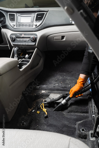 Vacuum cleaning of dirty car floor with removed seats in detailing service. Worker of detailing service is using vacuum cleaner for remove dust and dirt in car. © Rabizo Anatolii