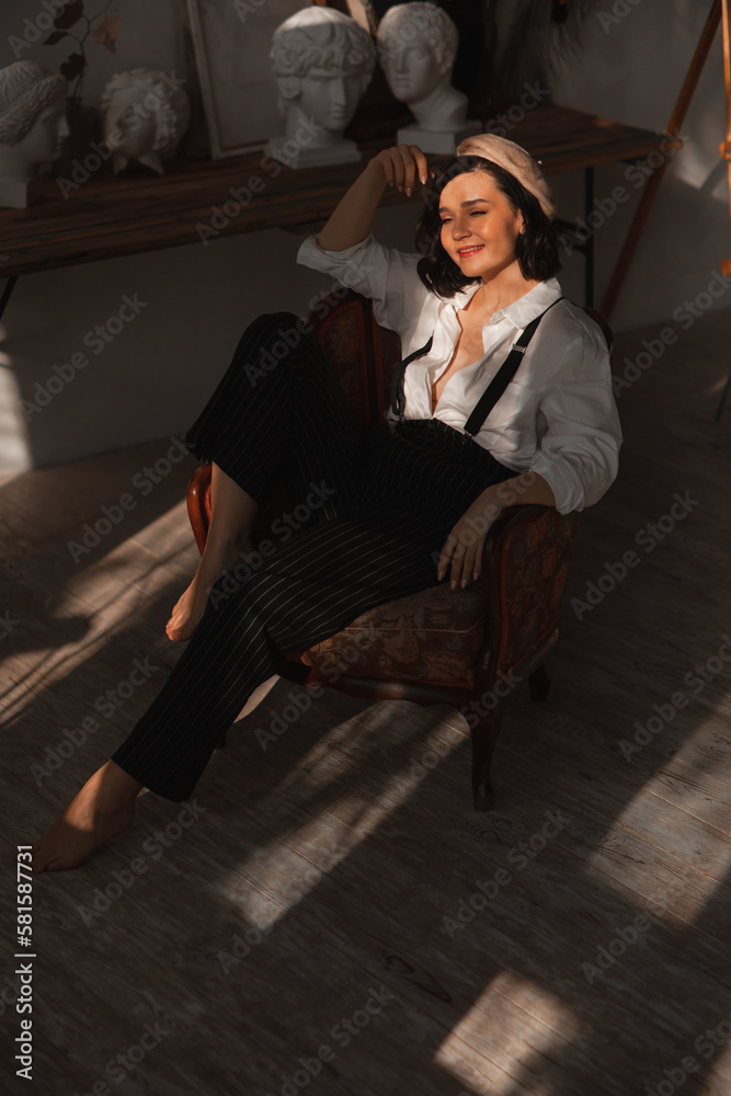 Obraz premium beautiful happy brunette woman in a chair in the rays of the sun from the window