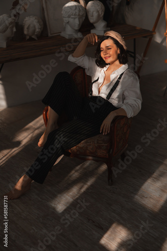 beautiful happy brunette woman in a chair in the rays of the sun from the window