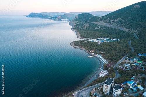 Fototapeta Naklejka Na Ścianę i Meble -  A delightful morning in a seaside resort with a picturesque winding coastline framed by mountains with juniper bushes. Shot from a drone.