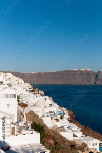 Vertical panoramic view of the white houses overlooking the Aegean Sea on the caldera of the island of Santorini in Greece with the background of the blue sky