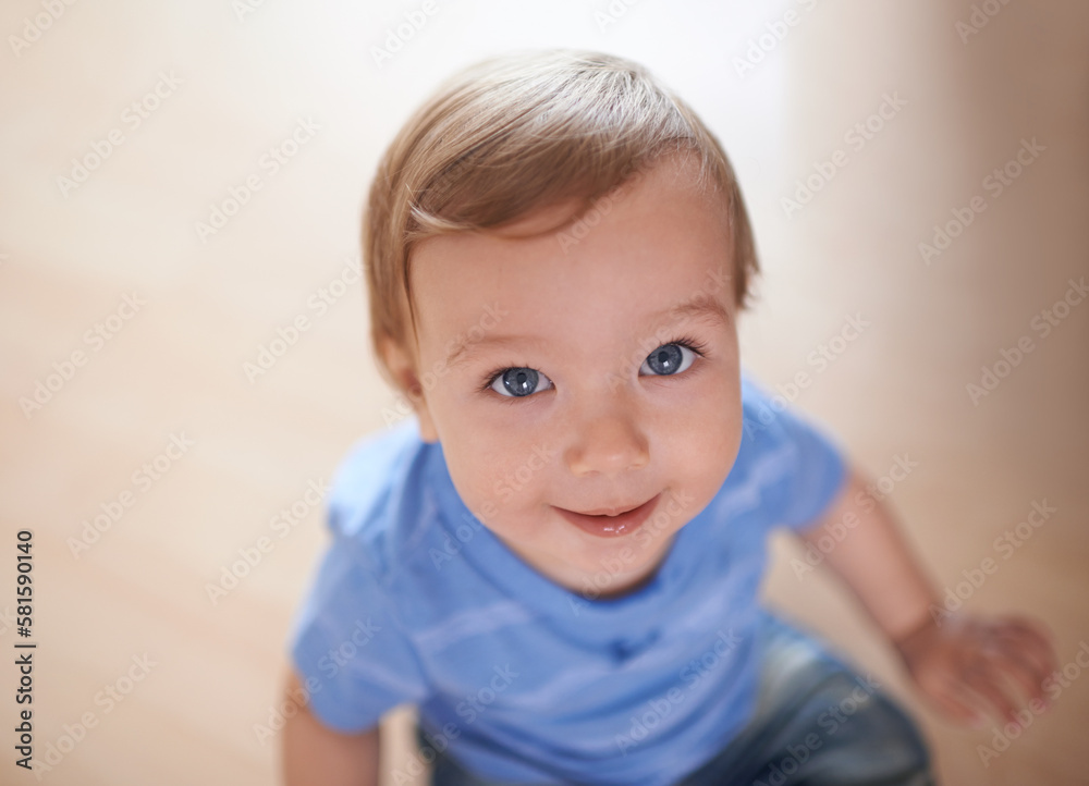 The cutest smile. an adorable little infant looking up at the camera from the floor.