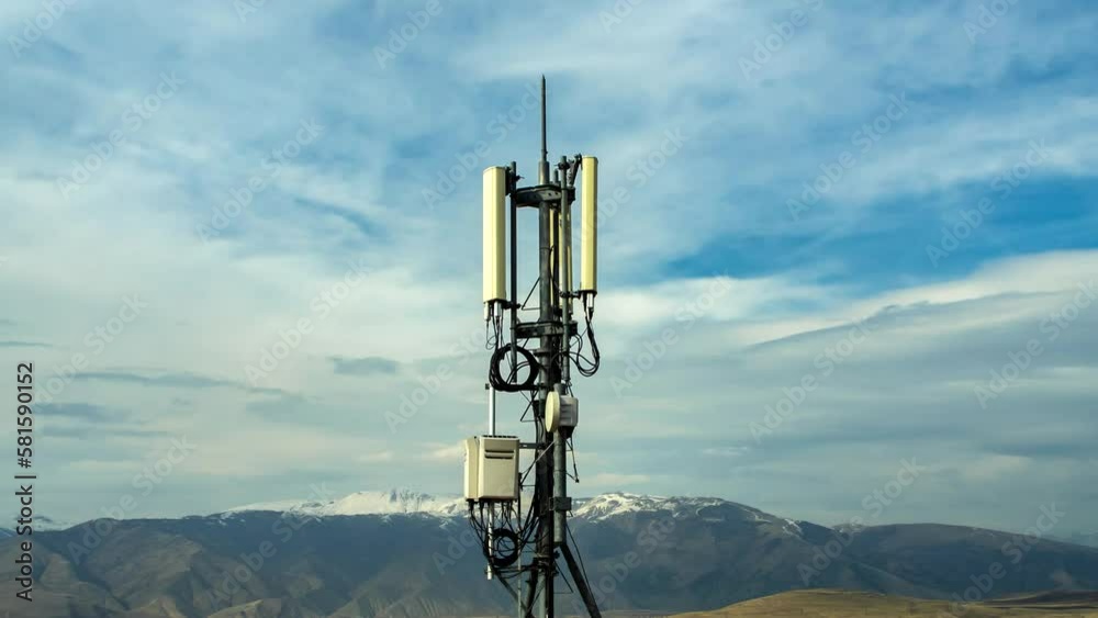 Time lapse telecommunications tower in the mountains tower with cellular transmitters and high speed internet 4G, and 5G and fast moving clouds on the blue sky. mobile communications in the mountains