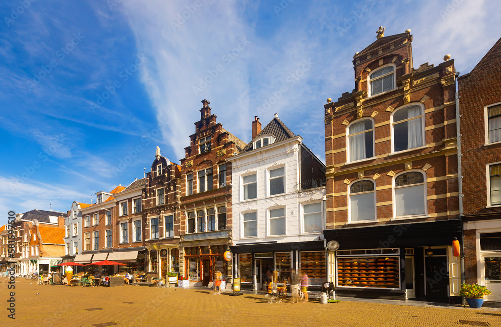 Scenic summer view of Delft cityscape overlooking peculiar townhouses on historical central Cameretten square and lively street cafes on sunny day, Netherlands