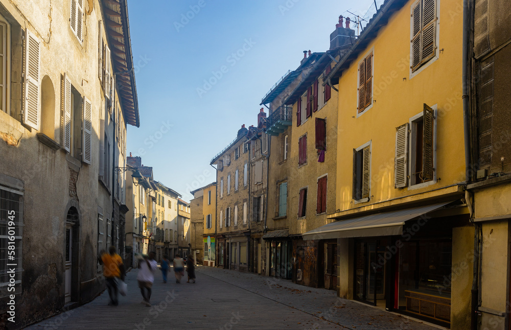 Narrow street of Aurillac, southern France. Rows of old-fashioned houses along paved walkway.