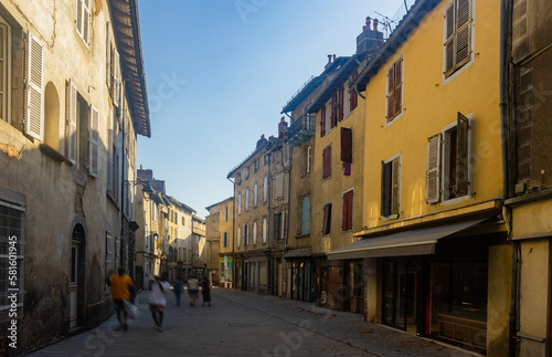 Fototapeta Naklejka Na Ścianę i Meble -  Narrow street of Aurillac, southern France. Rows of old-fashioned houses along paved walkway.