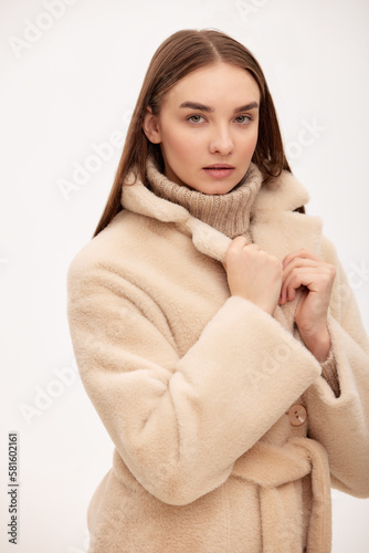 Close-up of a modern business woman on a light background in fashionable faux fur clothes, fashion, modern urban style