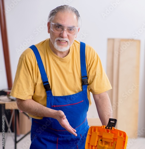 Old male carpenter working in workshop