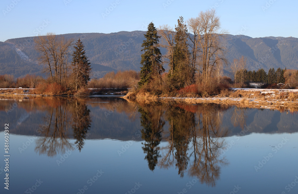 Winter scenery with trees reflected in calm river
