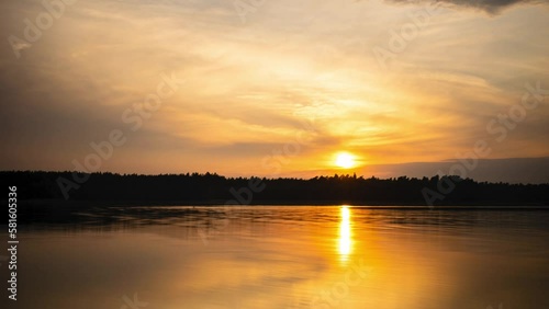Yellow sunset amidst the clouds over the calm surface of Lake Necko in Masuria, Poland
