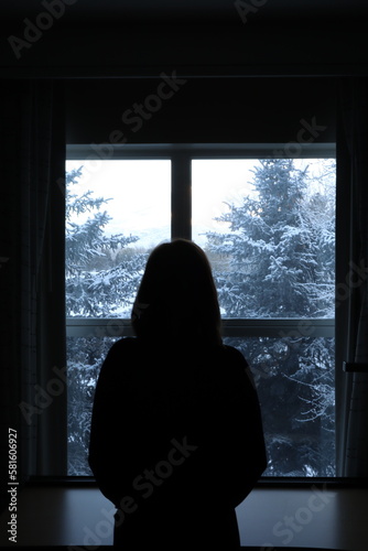 silhouette of a person looking out window © Alek
