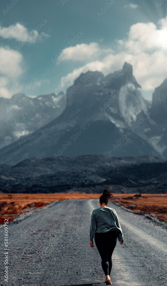 Fototapeta premium Girl Walking On Dirt Road In The Wind Towards Mirador Los Cuernos, Torres Del Paine, Patagonia,Chile