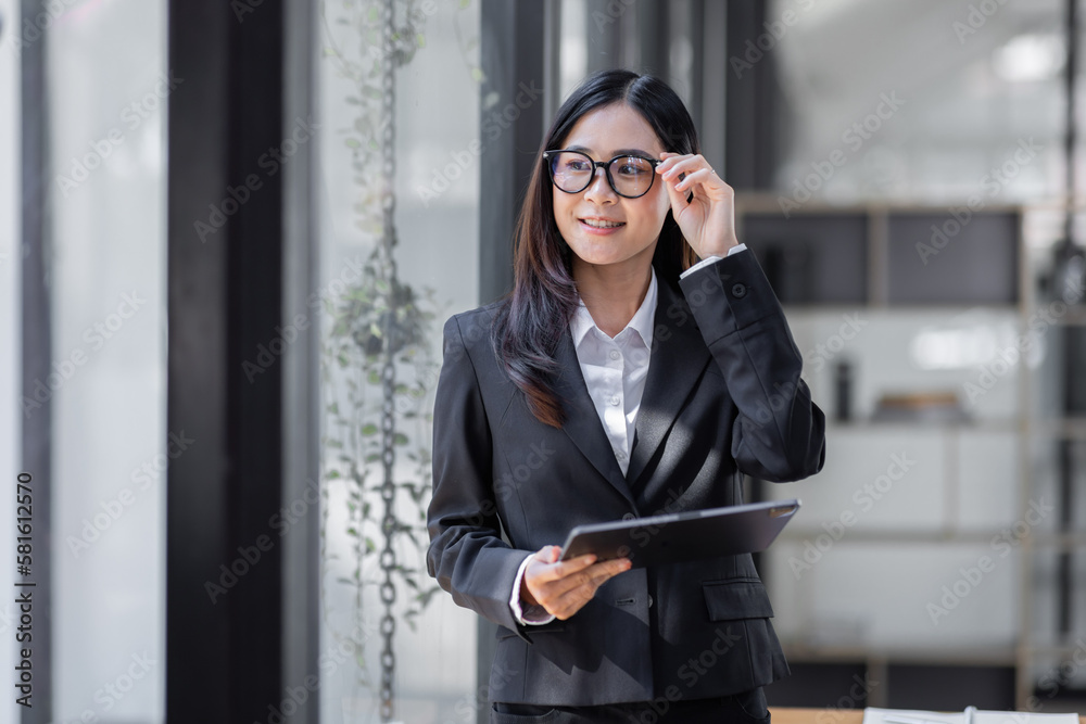 Portrait of Young business asian woman using tablet, standing in office.
Portrait of Young business asian woman using tablet, standing in office.