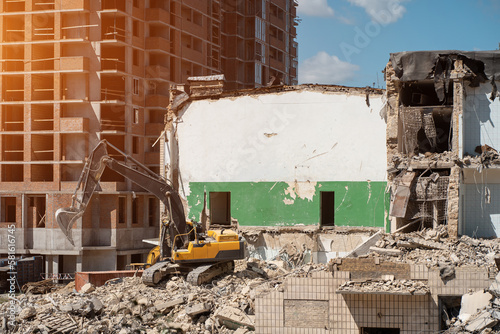 Εκτύπωση καμβά demolition old building by excavator near new construction of modern skyscraper