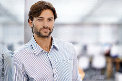 Hes a confident young businessman. Portrait of a handsome young businessman standing in his office.