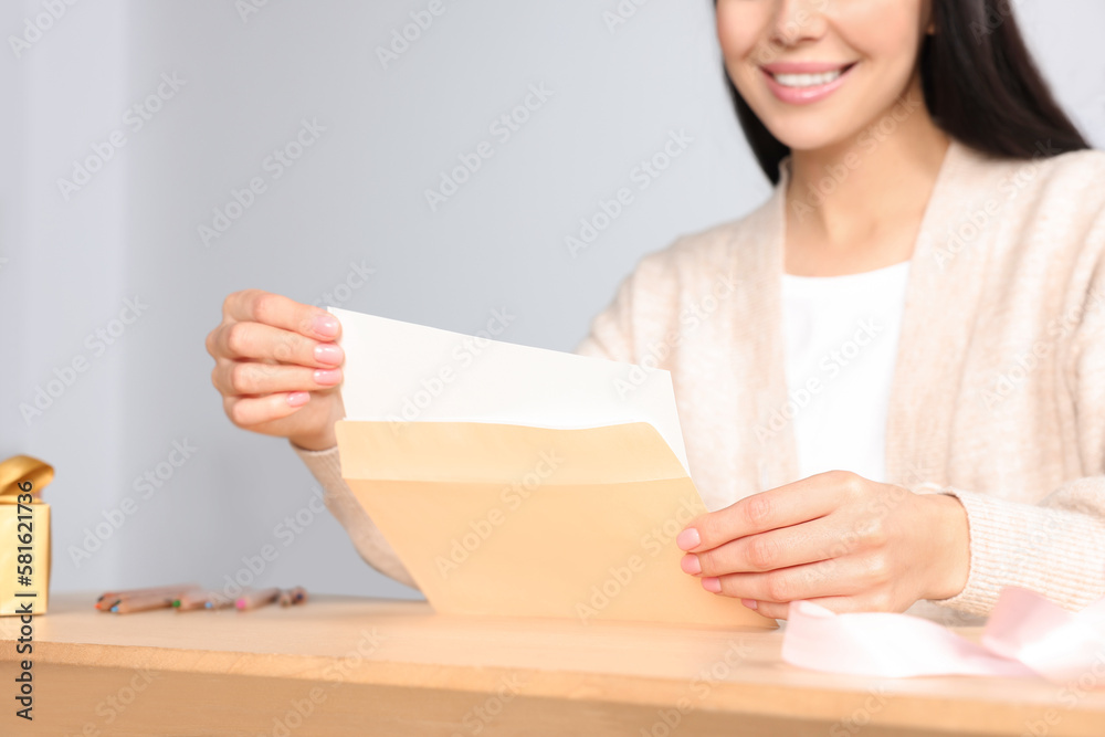 Happy woman holding greeting card at wooden table, closeup Happy woman holding greeting card at wooden table, closeup