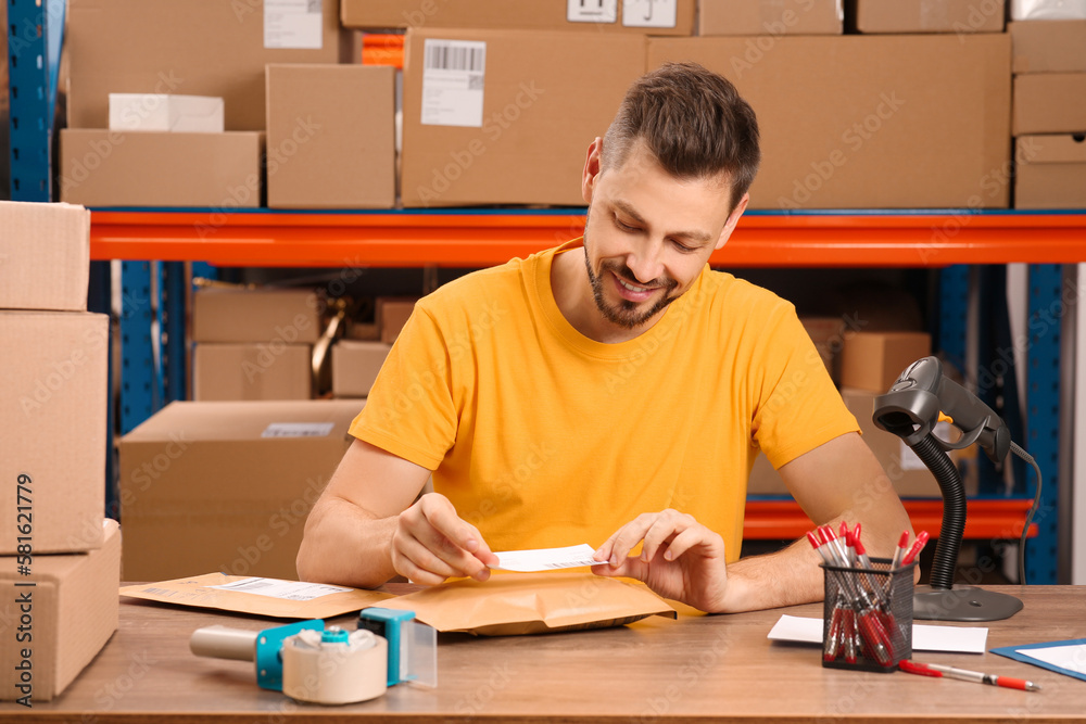 Post office worker sticking barcode on parcel at counter indoors Post office worker sticking barcode on parcel at counter indoors