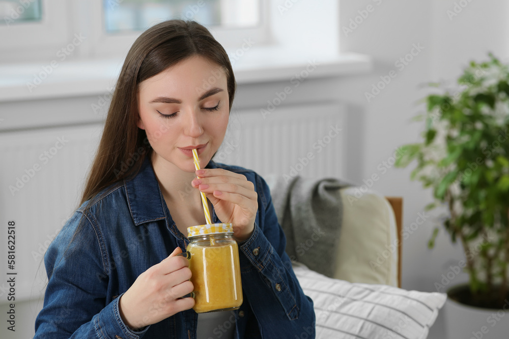 Beautiful young woman drinking delicious smoothie at home. Space for text Beautiful young woman drinking delicious smoothie at home. Space for text