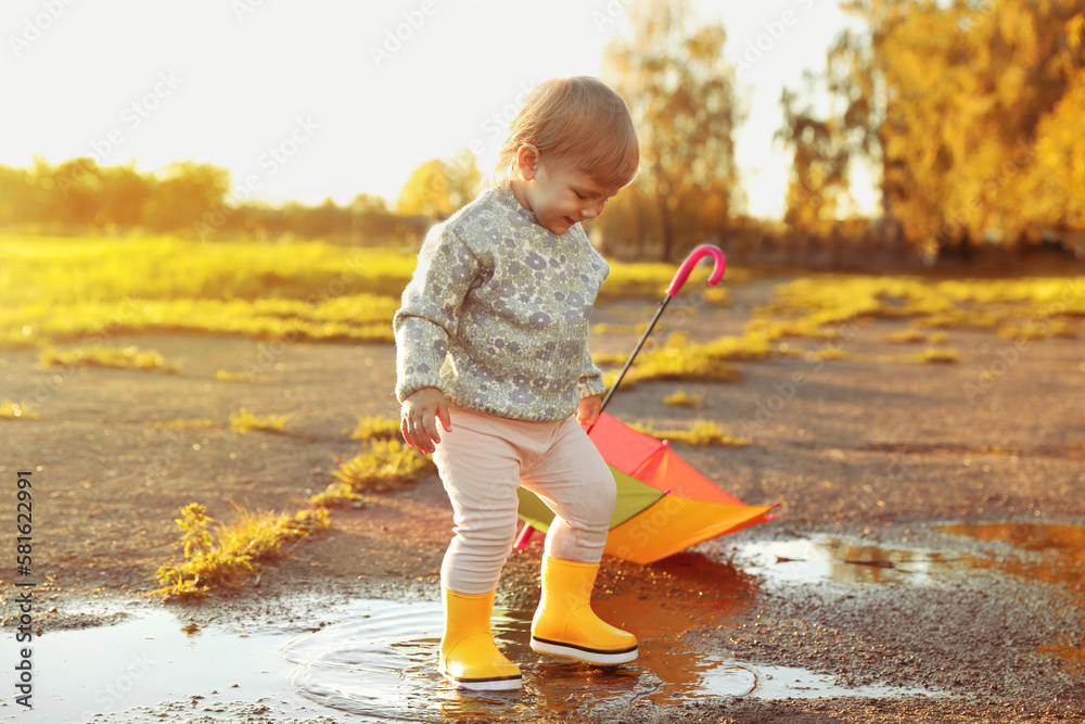 Little girl wearing rubber boots walking in puddle outdoors Stock Photo ...