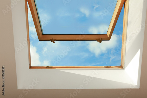 Bilde på lerret Open skylight roof window on slanted ceiling in attic room, bottom view