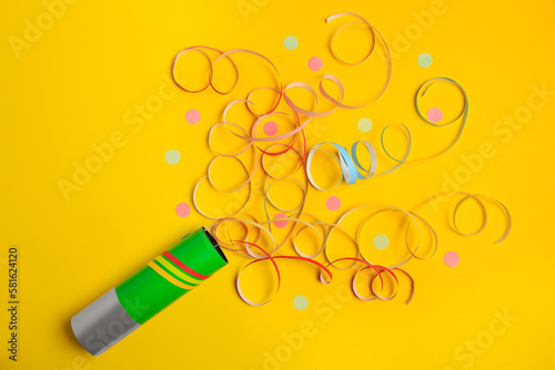 Photography Beautiful serpentine and confetti bursting out of party popper on yellow backgro