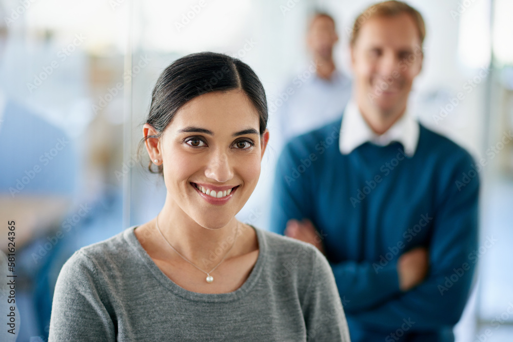 With great colleagues behind you success is inevitable. Portrait of a beautiful businesswoman standing in front of her colleagues in an office. With great colleagues behind you success is inevitable. Portrait of a beautiful businesswoman standing in front of her colleagues in an office.