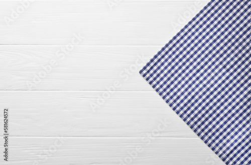 Blue checkered tablecloth on wooden table, top view. Space for text