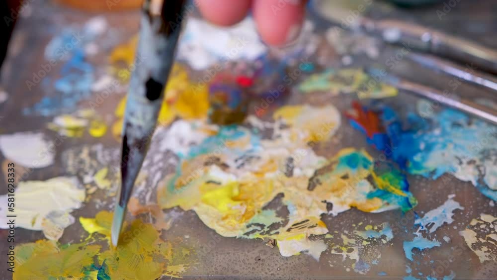 A set of bright saturated watercolors and brushes for painting in the artist's workshop. Mixed shades of paints on a plastic palette. Drawing and creative tools close-up. camera is in motion A set of bright saturated watercolors and brushes for painting in the artist's workshop. Mixed shades of paints on a plastic palette. Drawing and creative tools close-up. camera is in motion