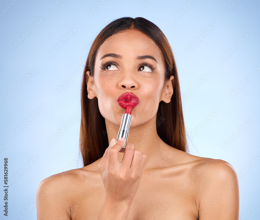 Beauty, woman and thinking about red lipstick or makeup with face cosmetics in studio. Aesthetic female model on a blue background to think self care, facial glow and color application for lips idea Beauty, woman and thinking about red lipstick or makeup with face cosmetics in studio. Aesthetic female model on a blue background to think self care, facial glow and color application for lips idea