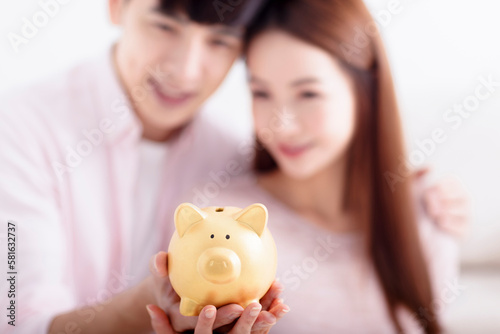Happy Couple holding Piggybank and Making Savings For Future