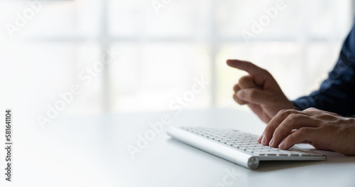 A man's hand is typing on a keyboard and the other is pointing the way to financial success. Performance and real estate growth , online business on Desktop computer in the office.