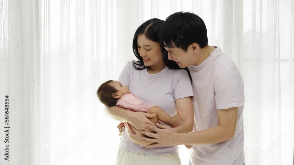 cheerful father and mother holding and hugging with newborn baby on white window background. happy family concept cheerful father and mother holding and hugging with newborn baby on white window background. happy family concept