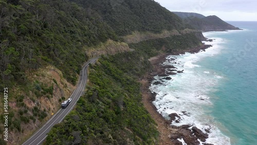 Car with caravan drives on Great Ocean Road next to coastal cliffs, Victoria, Australia photo