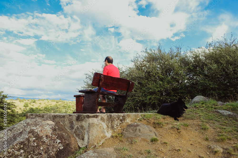 Obraz premium Older man drinking his morning coffee while resting and enjoying the view on the mountains. Beautiful rural landscape