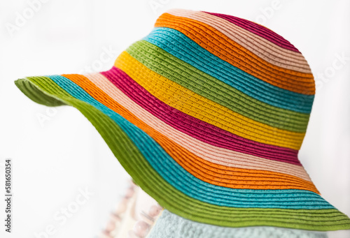 Straw multi-color summer hat on white background. Elegant hat with wide margins. Women beach, colorful stripped hat photo