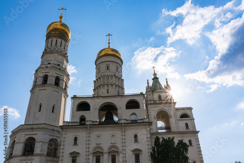 Ivan the Great Bell Tower, with Assumption Belfry on the right in Moscow Kremlin. Blue sky background with sunbeams