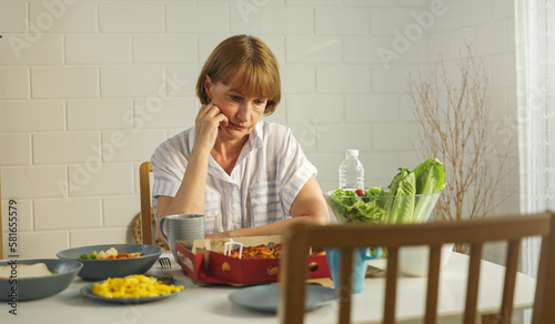 Elderly retired grandmother stay at home with unhappy face sitting alone on eating table in house. Depressed mature Senior old woman upset feeling lonely and missing her family at home.