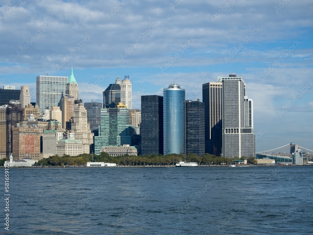 Looking back on Manhattan from the Hudson River and Liberty Island, as the towering high rises of Lower Manhattan loom above the river