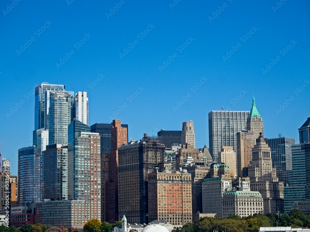 Fototapeta premium Looking back on Manhattan from the Hudson River and Liberty Island, as the towering high rises of Lower Manhattan loom above the river