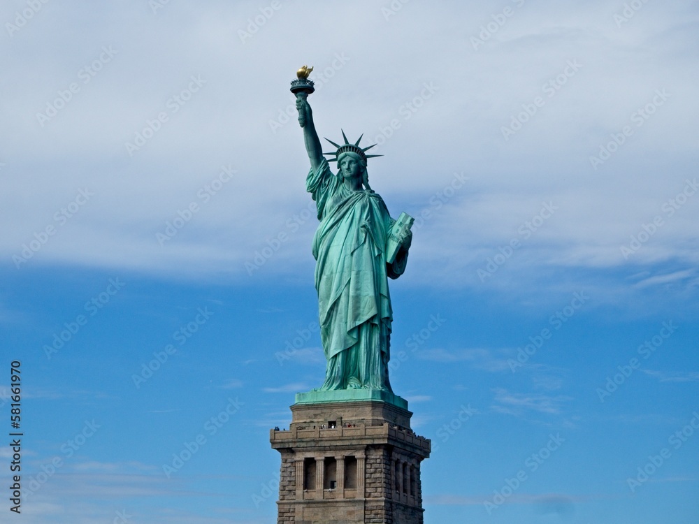 Fototapeta premium The Statue of Liberty sits on Liberty Island in the New York Harbor. It was once a beacon of hope for immigrants arriving by steamship into the United States