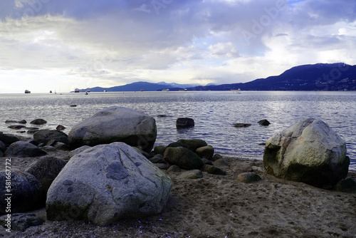 View of ships moored in English Bay from Kitsilano Beach with boulders in the foreground in the late afternoon