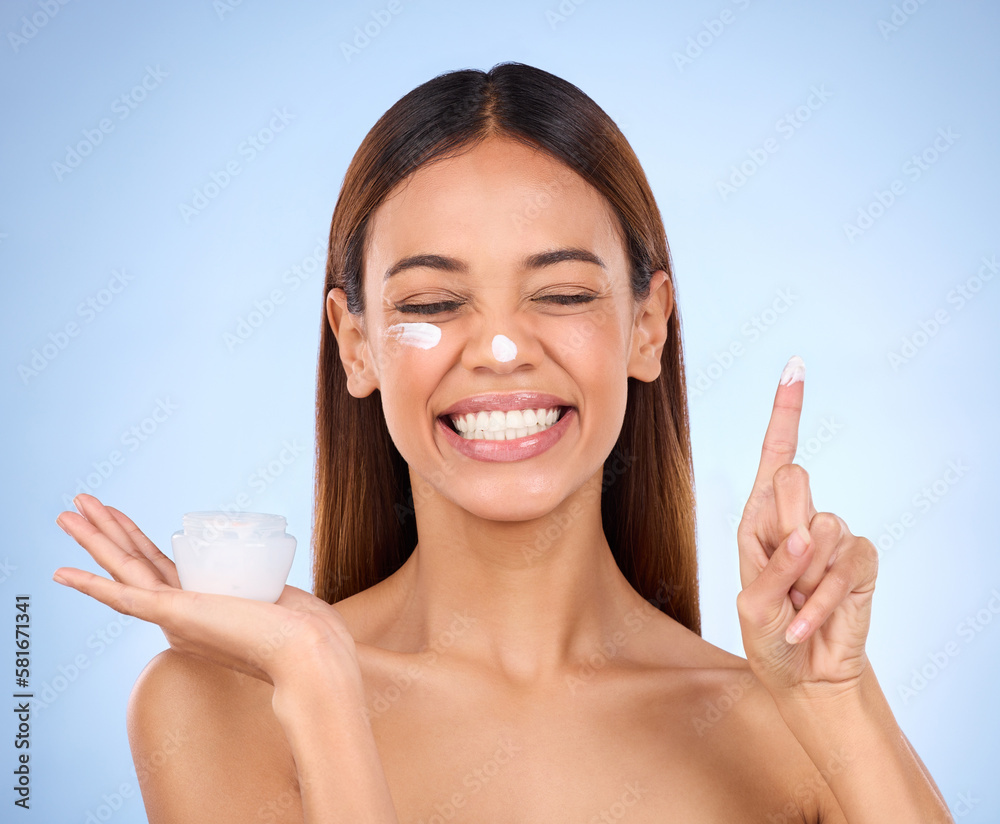 Woman, face and moisturizer cream for beauty skincare cosmetics, self love or care against blue studio background. Happy female with lotion or moisturizing creme for perfect skin or facial treatment Woman, face and moisturizer cream for beauty skincare cosmetics, self love or care against blue studio background. Happy female with lotion or moisturizing creme for perfect skin or facial treatment