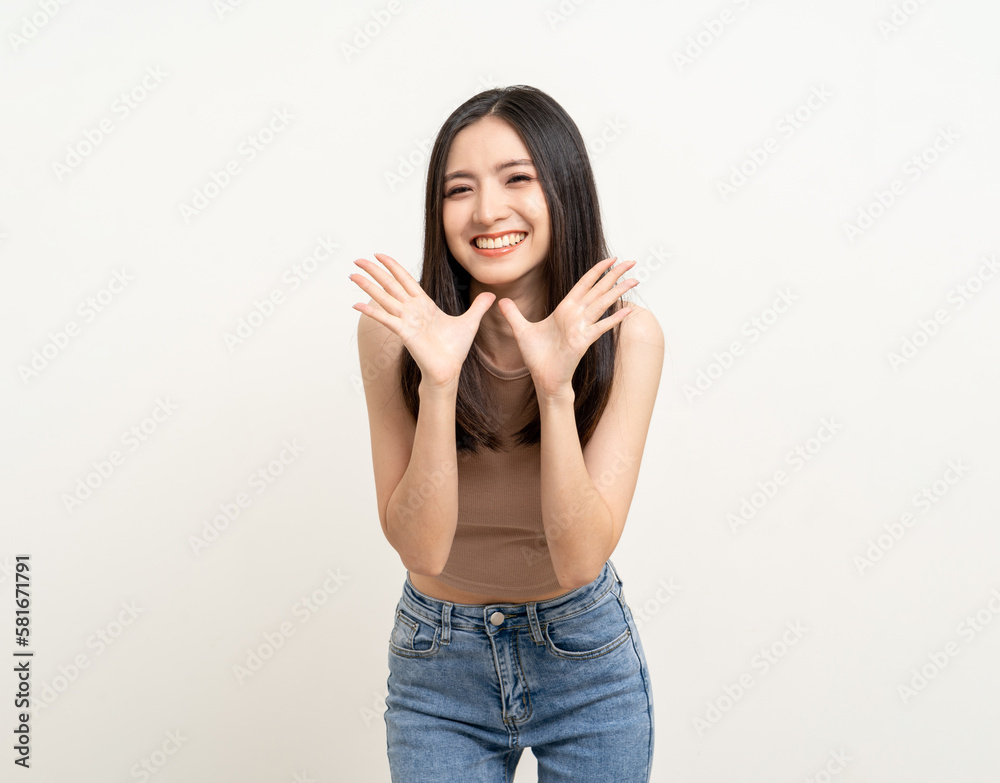 Happy beautiful asian woman pointing finger to copy space. Excited pretty girl shout out loud wow with hands on mouth announcement standing pose on isolated white background.